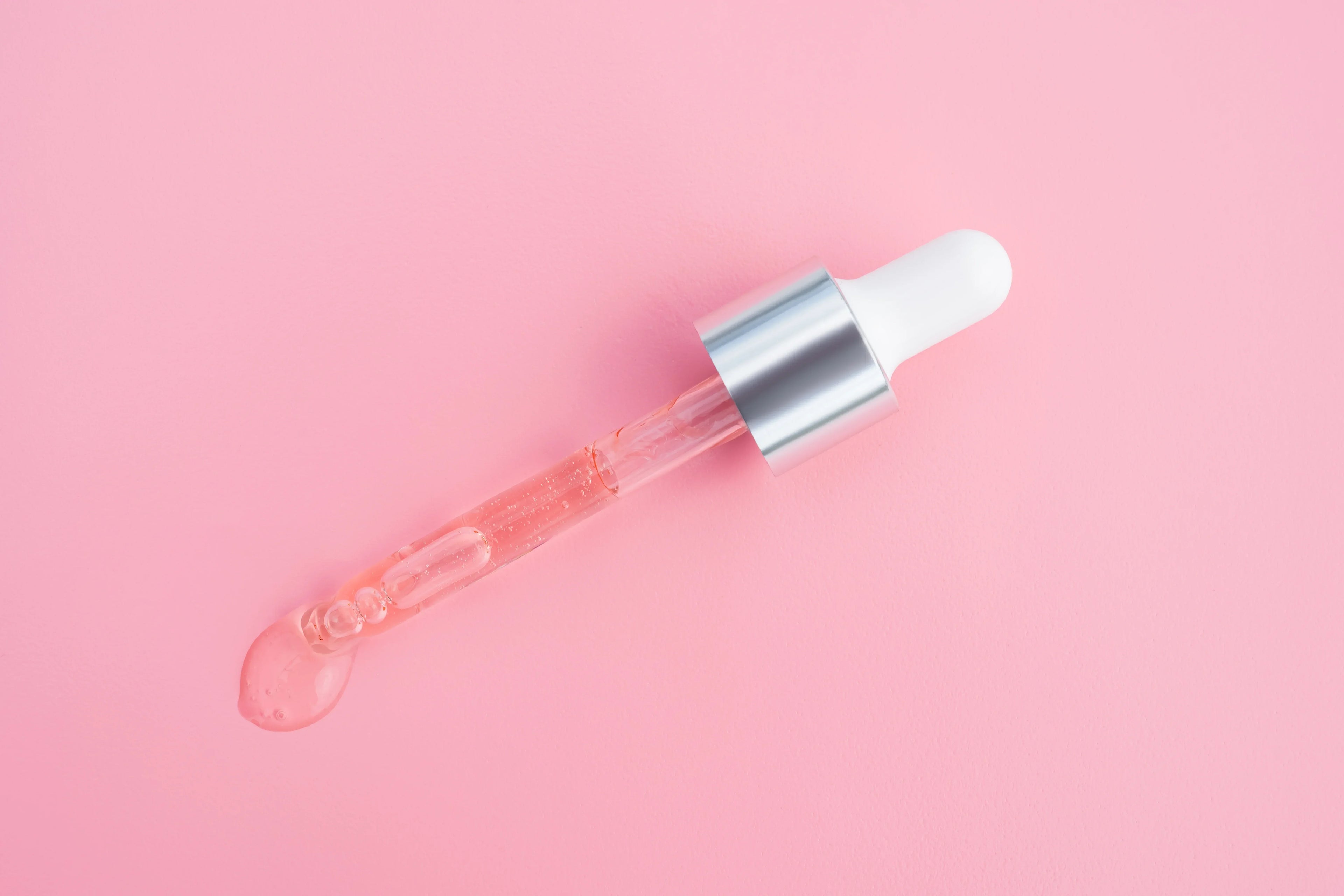 Pink serum dropper on a pink background