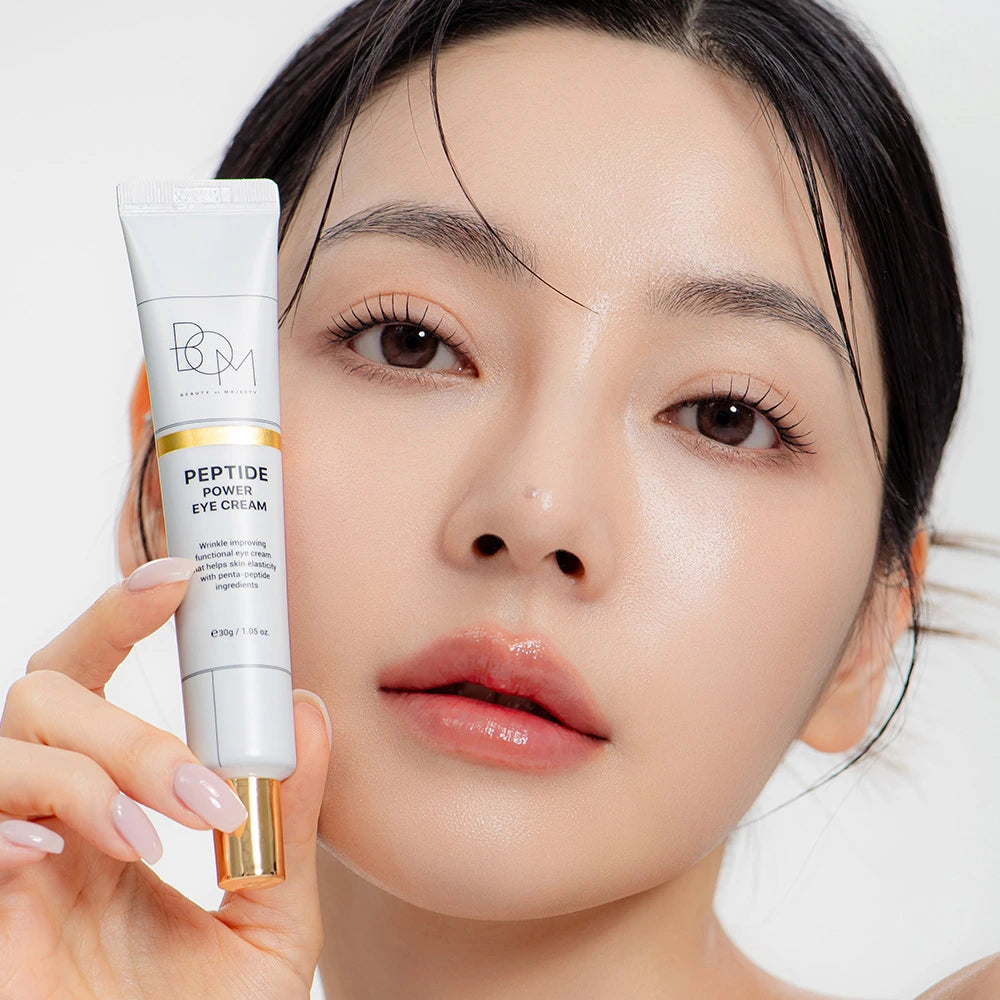 Femme tenant un tube de crème contour des yeux BOM Peptide Power sur fond blanc