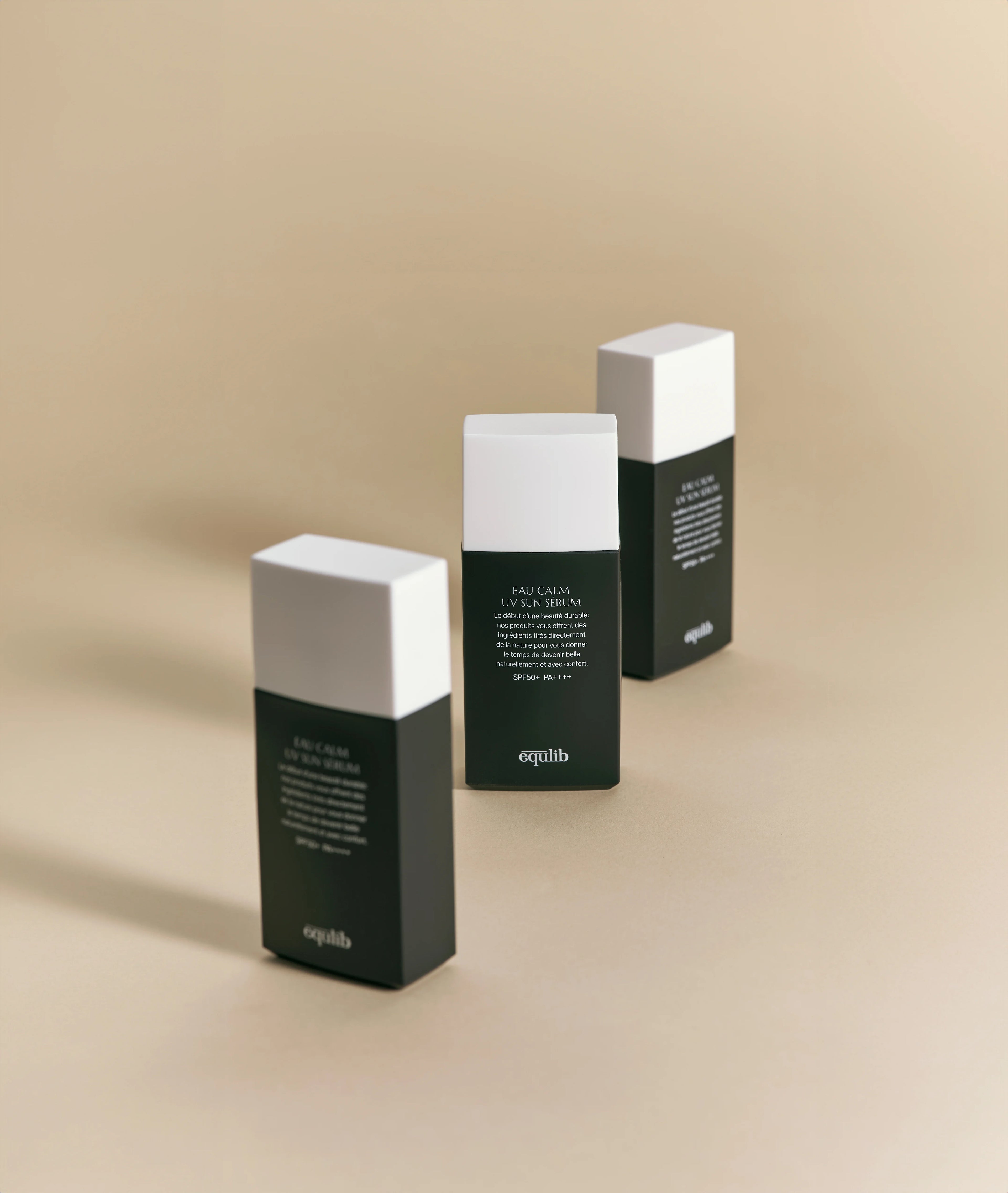 Three Equlib Eau Calm UV Serum SPF50+ PA++++ bottles with green and white packaging on a beige background