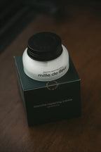 Mille de Fleur Blanche Repairing Crème lid on its green box on a wooden surface